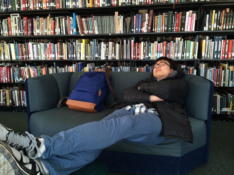 In a library, Chul naps on a small couch with feet up on a table