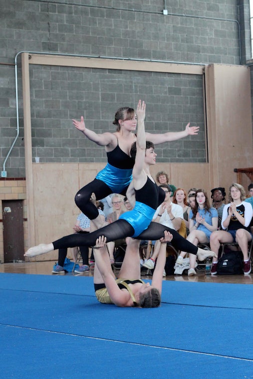 One performer laying on the mat holds up two others in a pose.