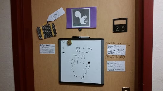 A door has a whiteboard with the outline of a hand drawn as a turkey. A note says 'Have a GR8 Thangsgiving!'