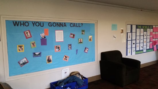 A bulletin board labelled 'Who you gonna call?' has photos of about a doxen people.
