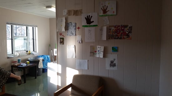 A wall in the kitchen has papers, drawings, and cards tacked onto it.