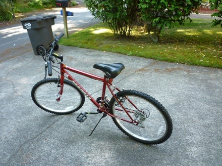 A bike in a driveway held up by a kickstand