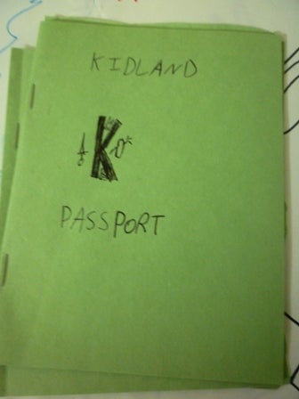 A construction paper booklet titled Kidland Passport with an official-looking letter K logo at the center.