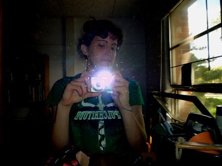 A young man takes a flash photo in the mirror.