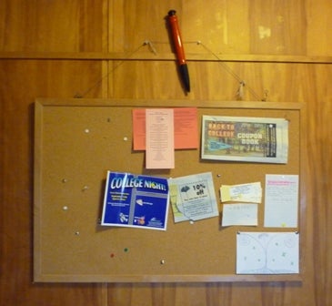 Bulletin board with a few papers on it.
