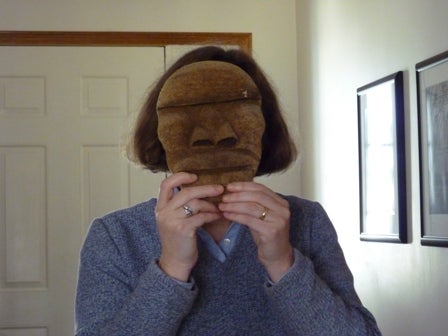 Woman holds a mask in front of her face 