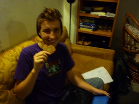A young man on a couch eats a cookie.