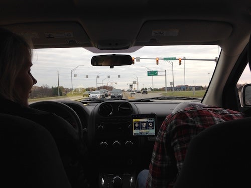 A view from the backseat of the car. In the front sits the authors mom and brother. They are driving on highway