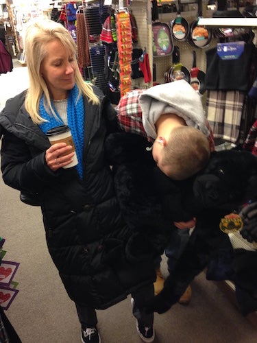 The authors mom and brother in Ben Franklin. The mom is holding a cup of coffee and gazing at the brother who is hugging a giant gorilla stuffed animal 