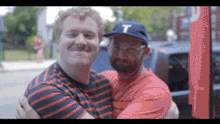 A gif of two men embracing and posing for the video. The animated words "everything looks glamorous from a distance" appear 