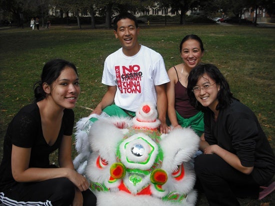 Four people with the lion costume. One wears a shirt that reads 'No casino in Chinatown.'