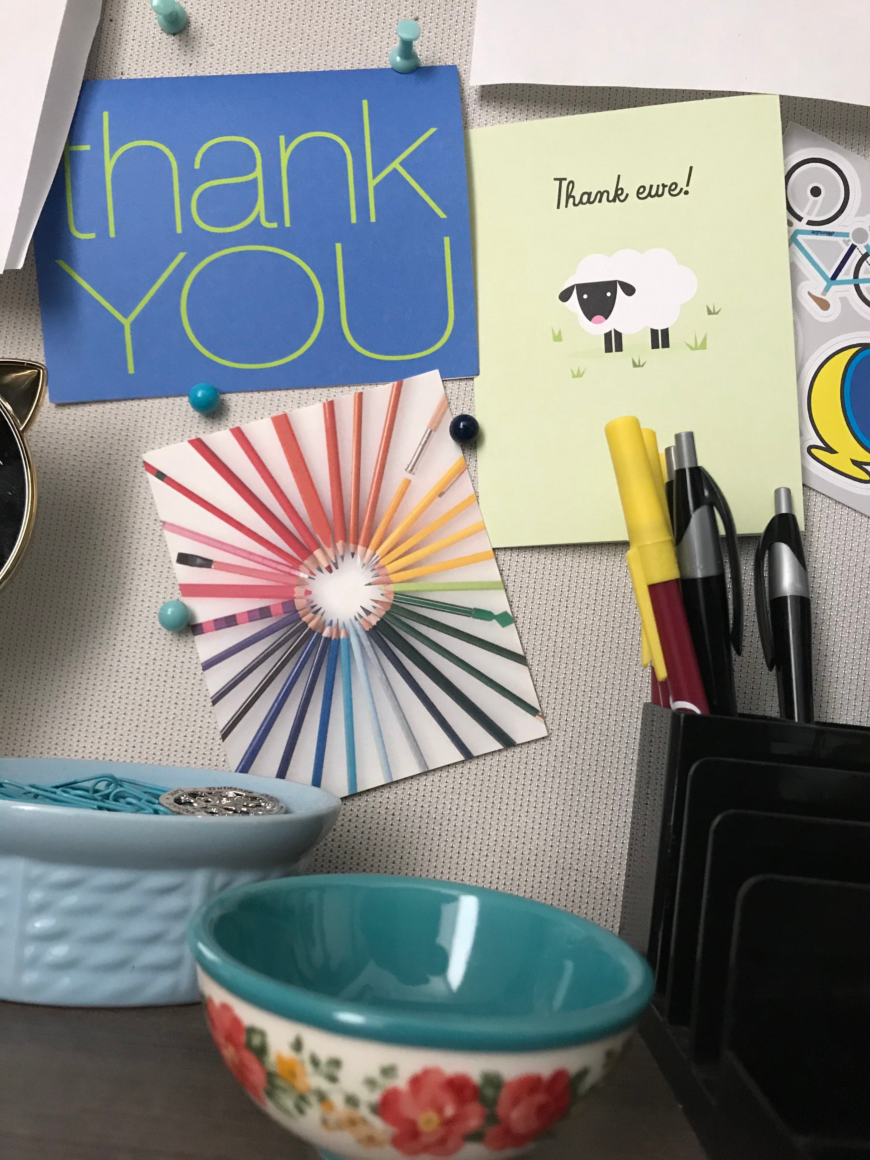 A desktop with a pin board containing three thank you cards.