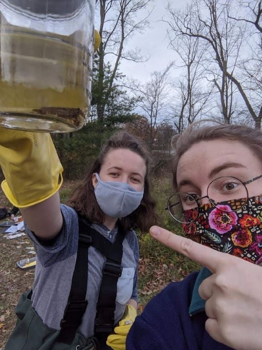 Me and my lab partner, wearing masks, take a selfie with a crayfish