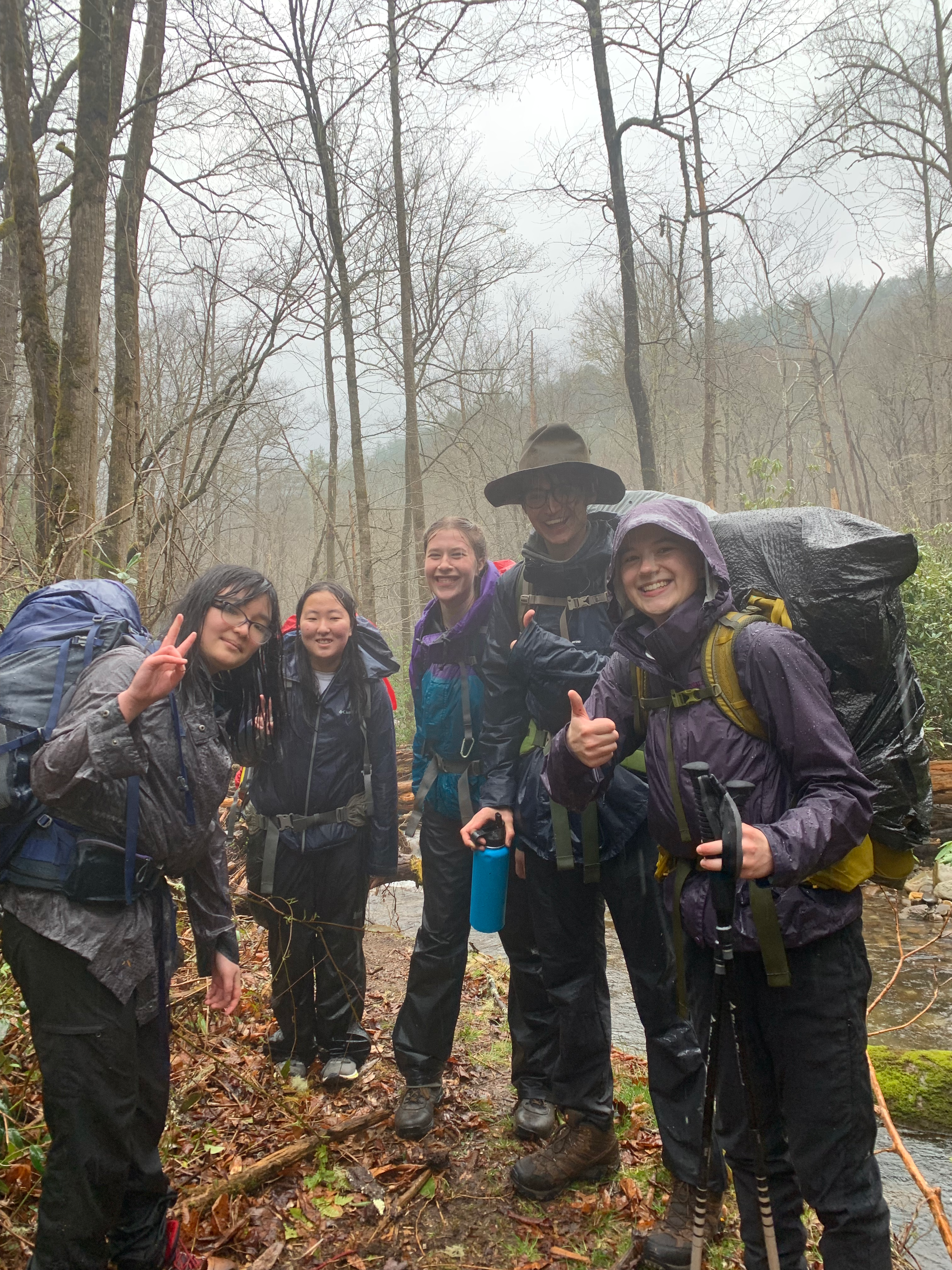 five people in very wet rain gear smiling at the camera