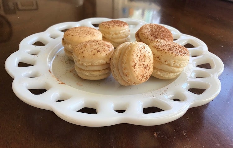 A photo I took of several pale beige macarons dusted with cocoa powder and arranged on a white plate