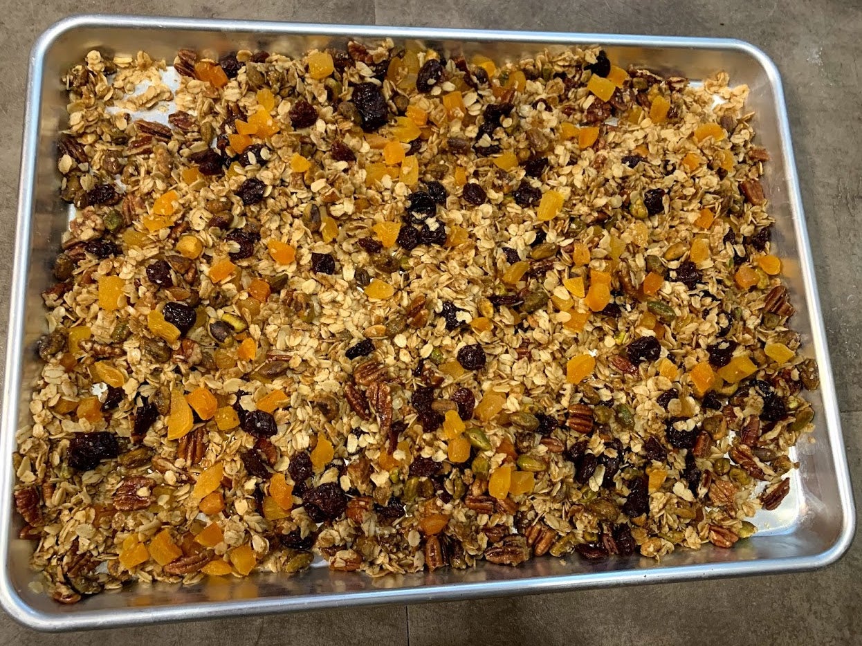 Toasted oats, dried fruit, and nuts sit together on a silver sheet pan.