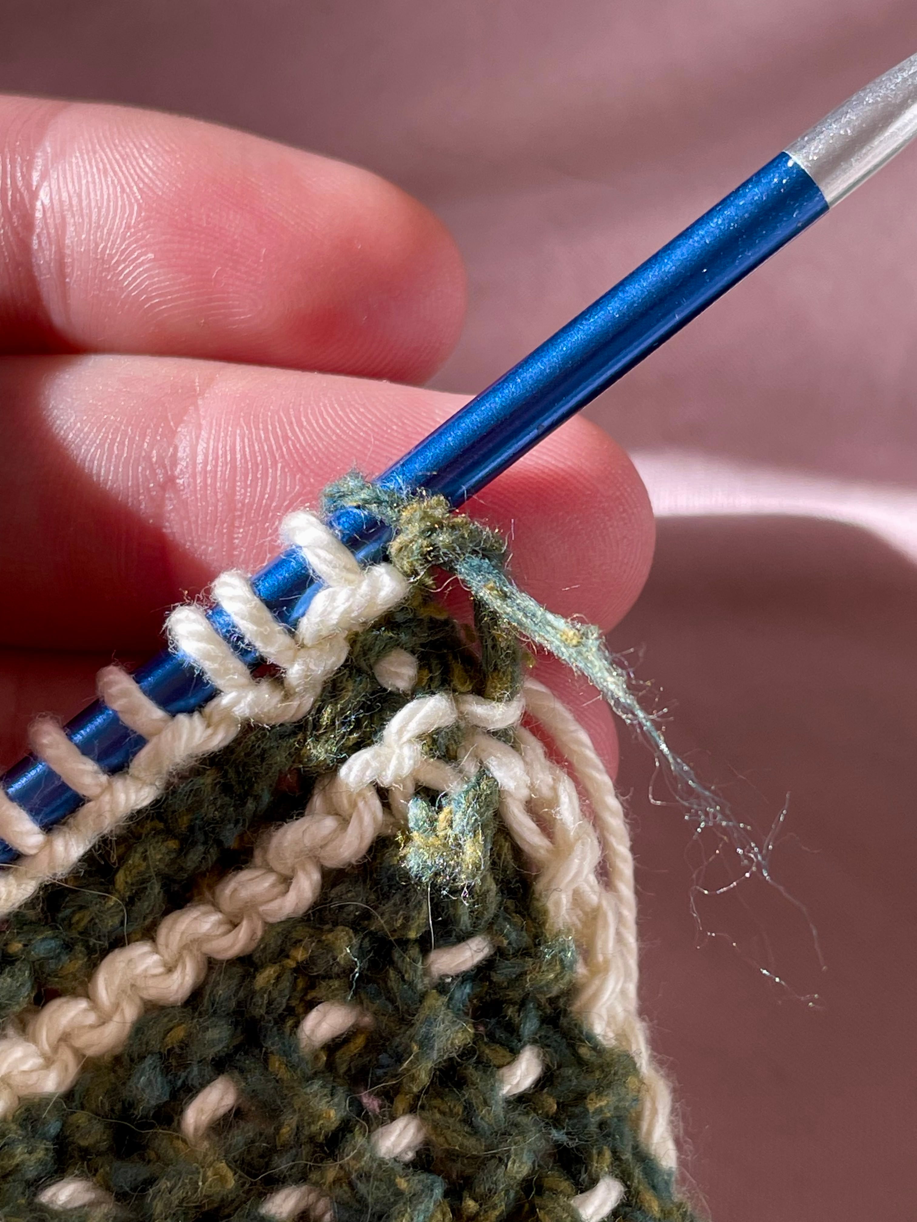 A green strand of broken yarn sticks out from the blanket.
