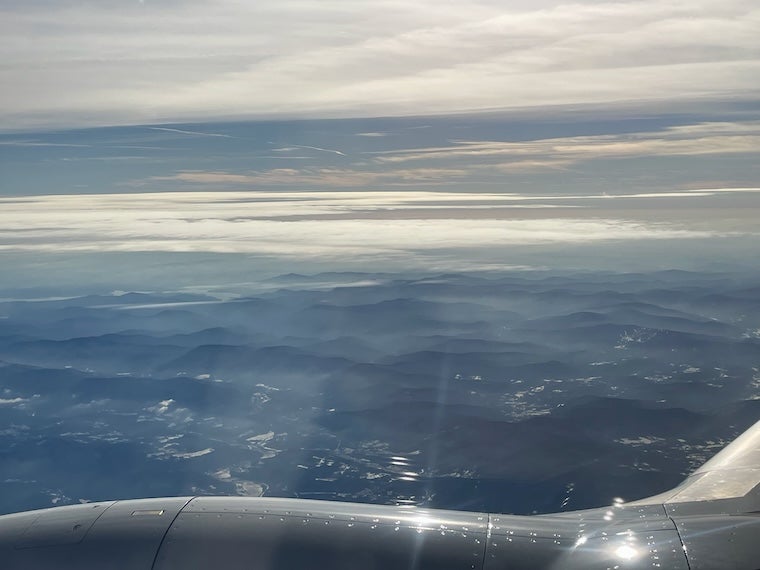 The view out a plane window showing foggy mountains