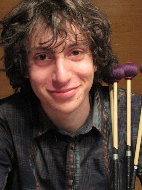 A headshot of a male student holding mallets.
