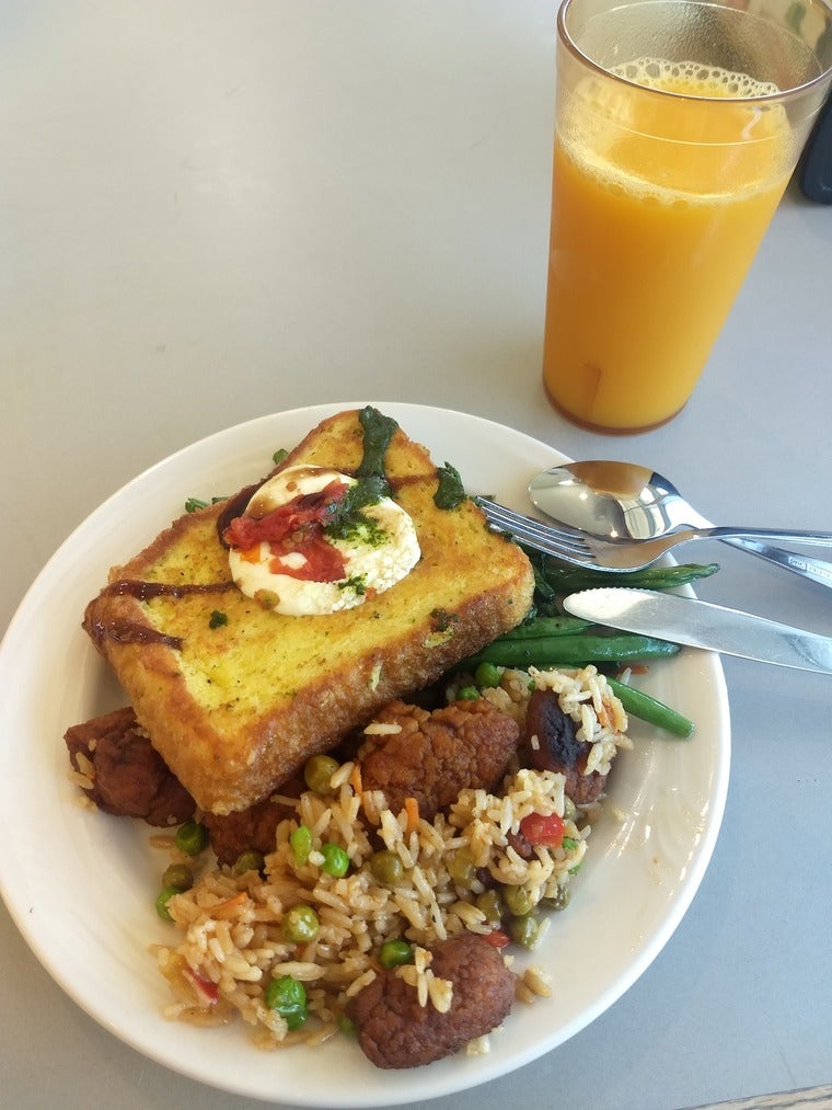 A plate of caprese toast and fried rice, next to a glass of orange juice