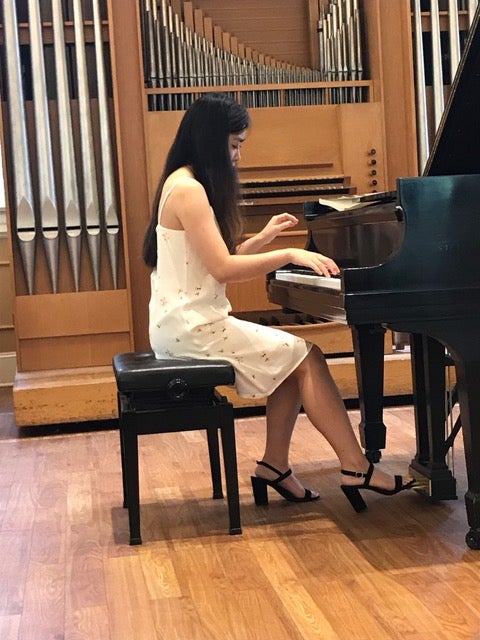 A girl is sitting playing piano