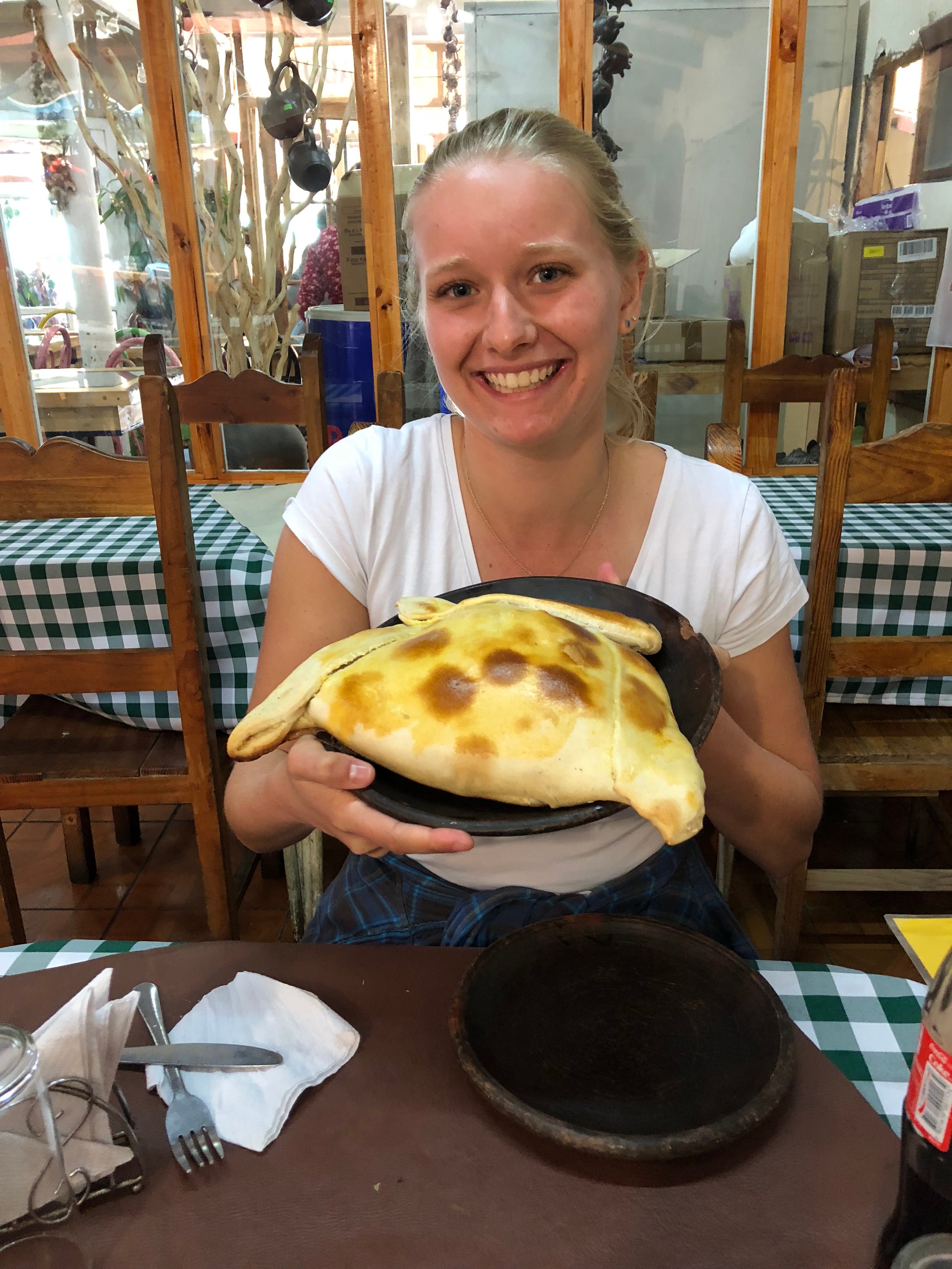 Sarah holding up a plate with a giant empanada