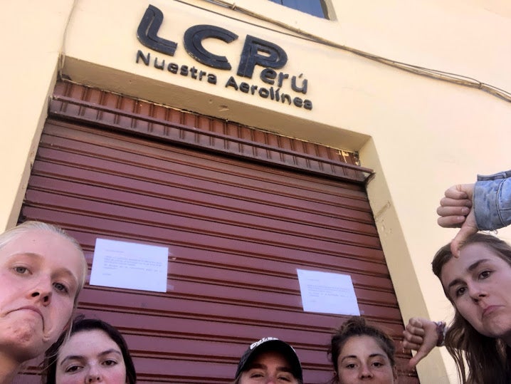 Five girls stand frowning in front of a closed store with a sign that says "LCPerú"