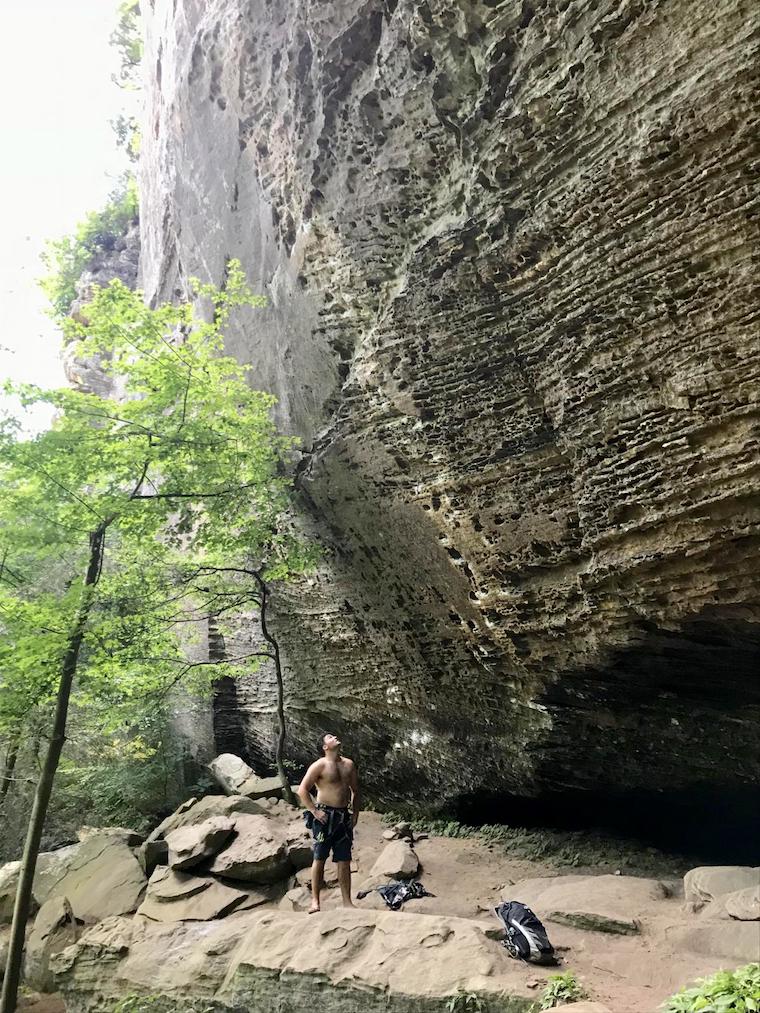 Teague looks tiny looking up at a giant rocky cliff
