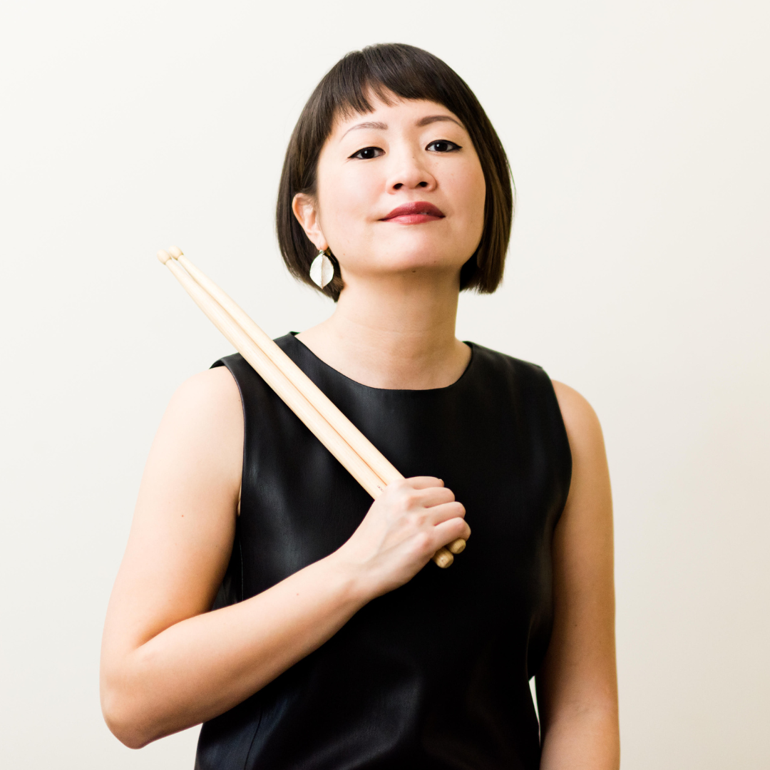Asian woman holding drumsticks wearing black clothes