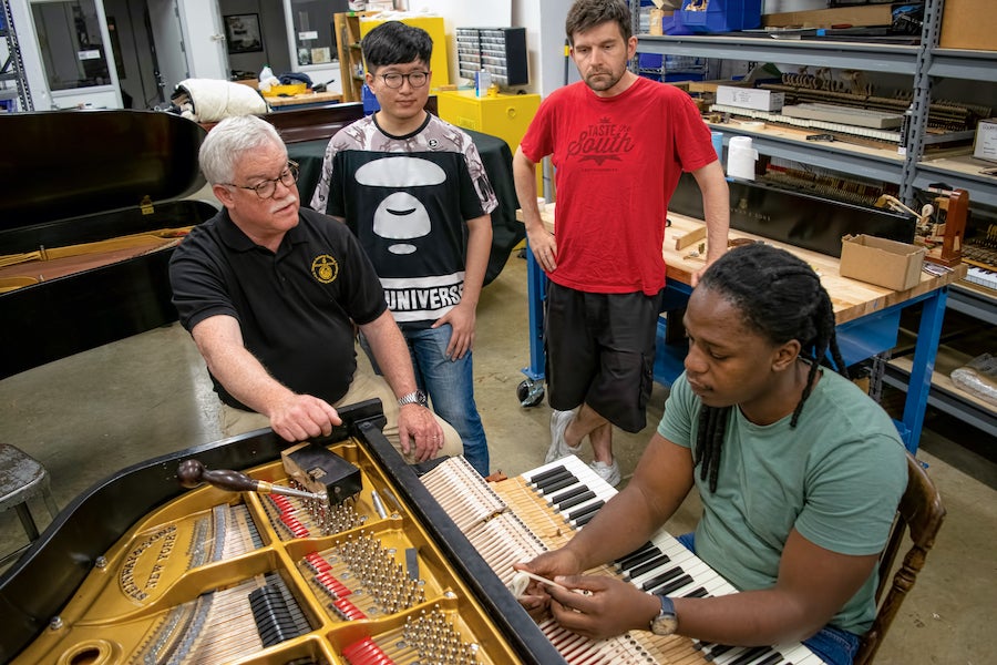 Piano technology students learning at a keyboard.