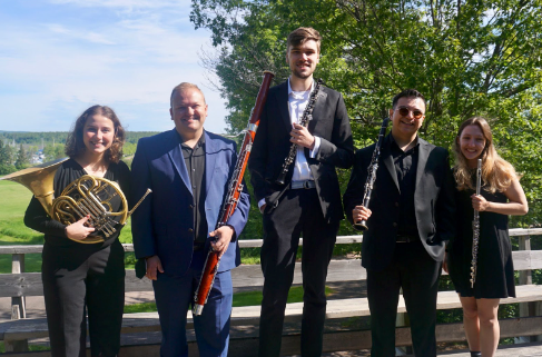Bebe stands with a woodwind quartet in formal attire holding their instruments