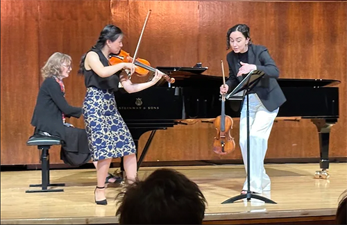 Student violinist and teaching violinist on stage