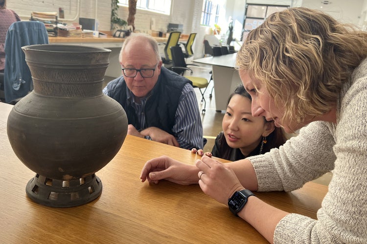 Joanne Kim and others observe a piece pulled from a group of ceramics from Korea's Three Kingdoms period, (ca. 57 BCE-676 CE).