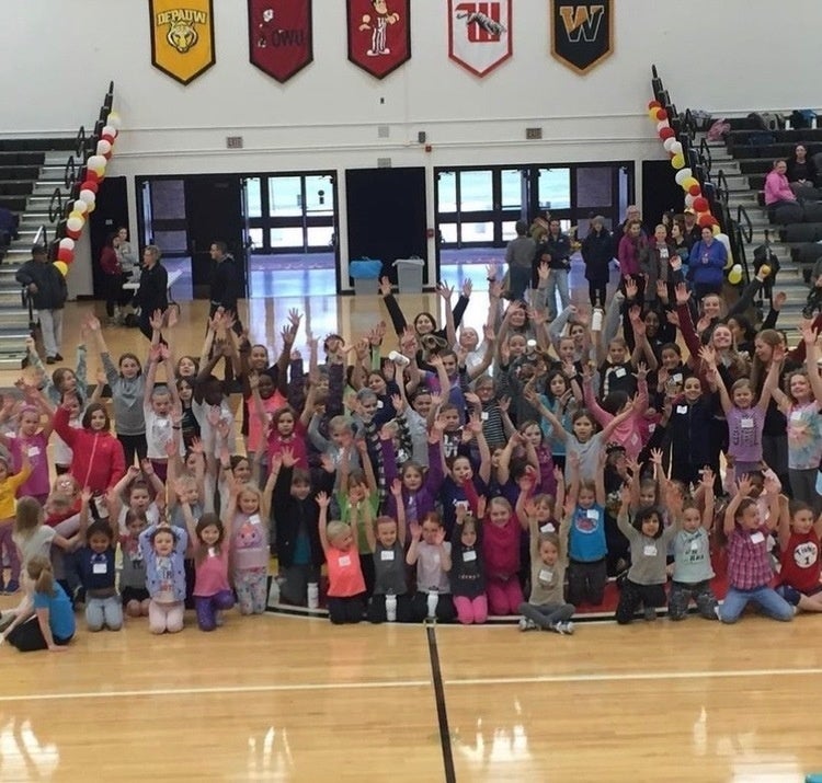 Kids in a gym raising their arms