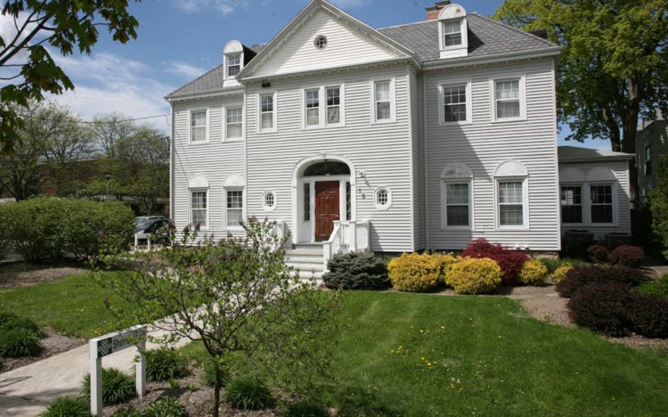 Photo depicts Shansi House, a three-story, grayish-white house along East College Street.