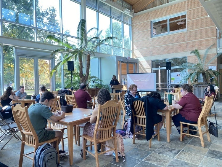 Tables of people watching a presentation in a sunlit room
