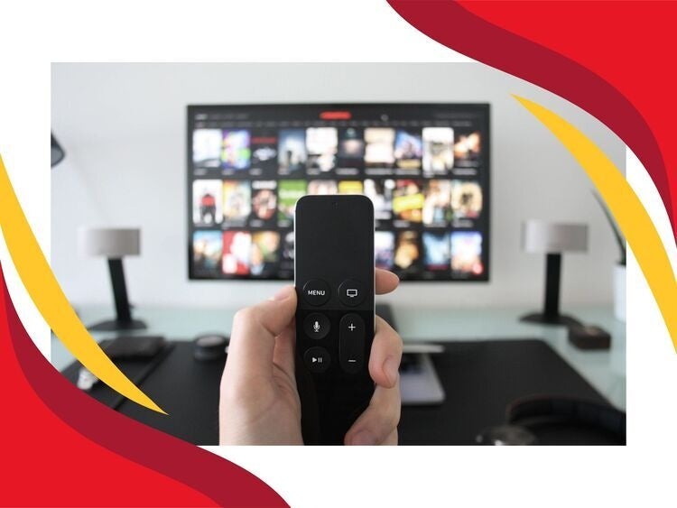 A white hand holding a remote control in front of a TV
