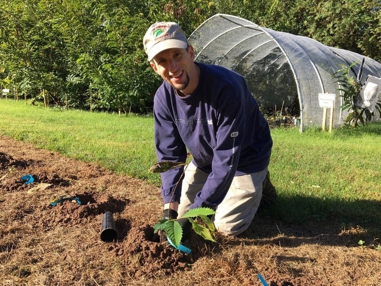 Andrew Newhouse in gardening gear, knelt down, hands in the dirt