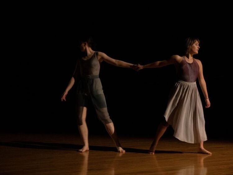 Two dancers holding hands pulling away form eachother.