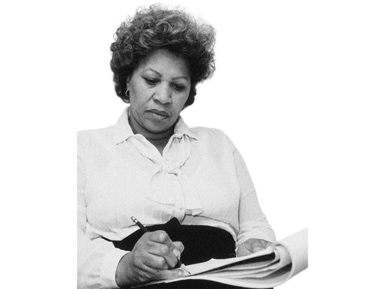 Black and white portrait of author Toni Morrison writing on paper