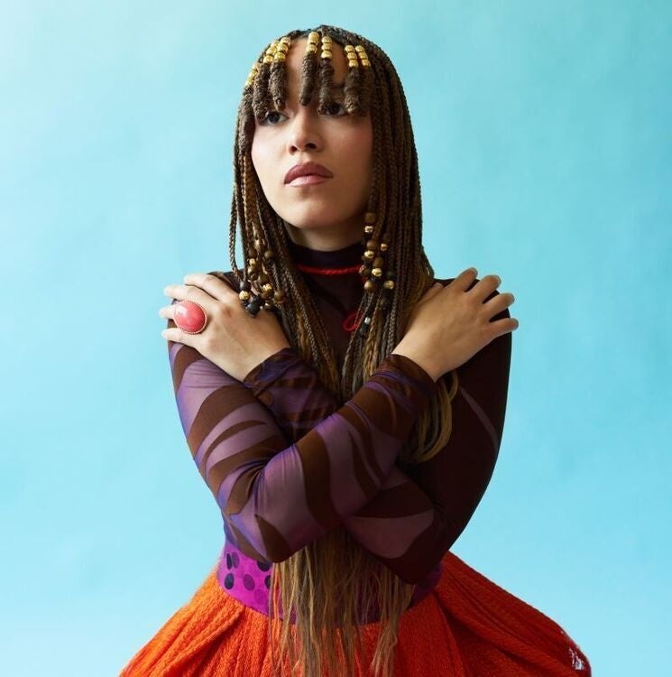Image of folk singer Kaia Kater posed with arms crossed across her chest. 