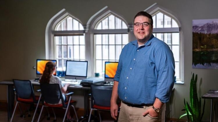 Man poses for photo in front of computers