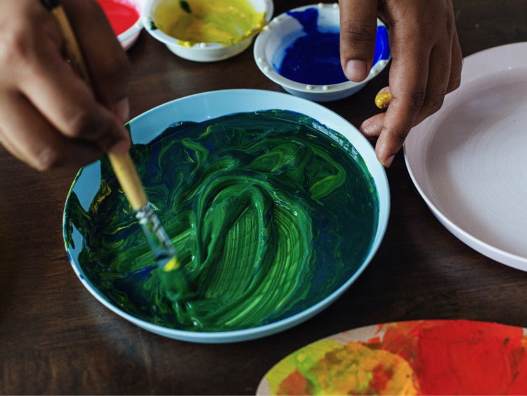 Hands mixing a bowl of paint