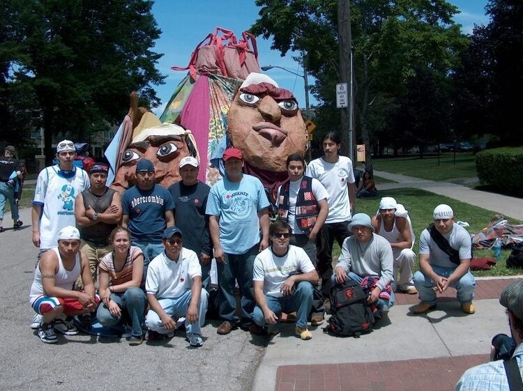 Group of people posing outdoors in front of large papier-mâché puppet heads
