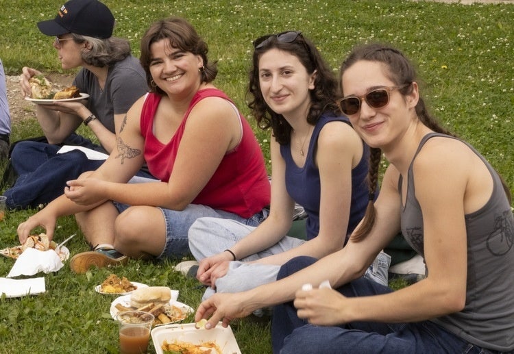 Three Oberlin students sitting in the grass eating a meal together.