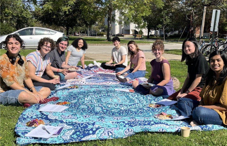 Students in a dialogue group sit in a circle outside.