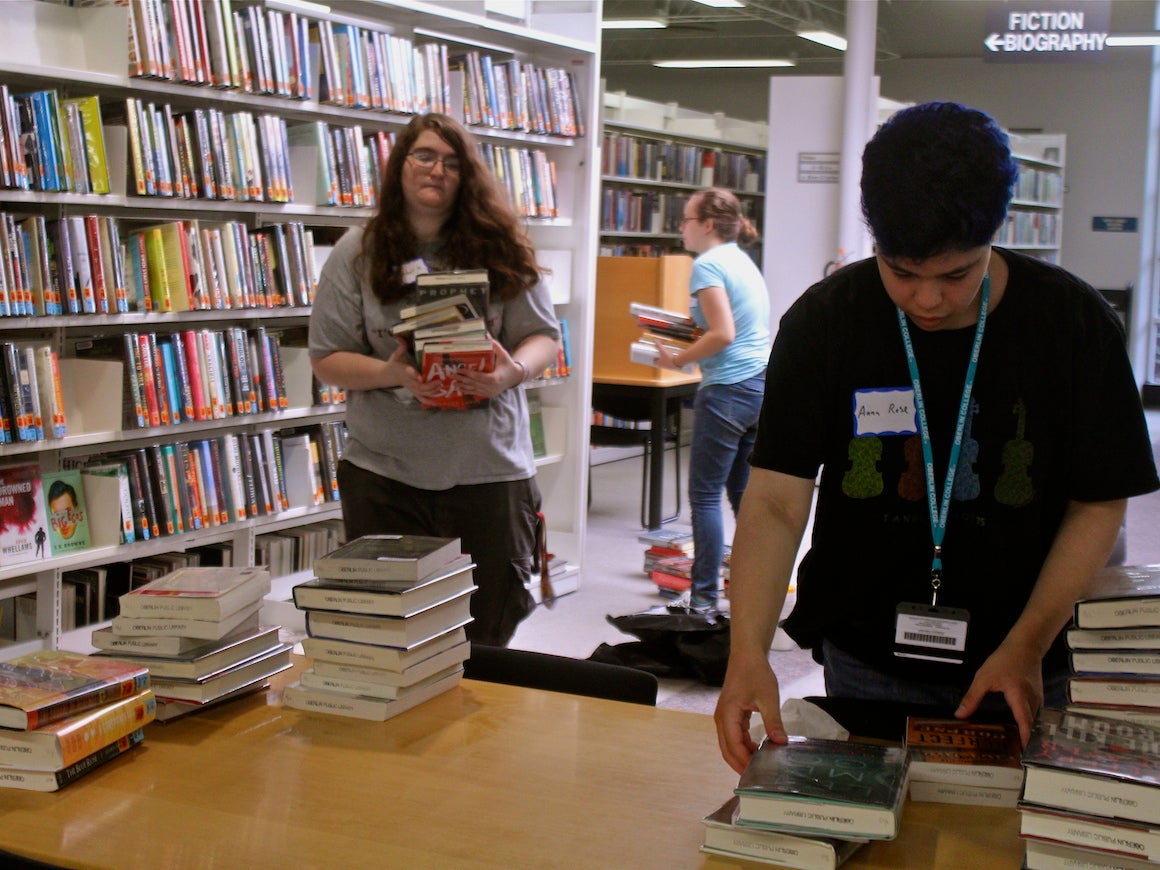 Two people organize books at a table.