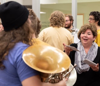 A lady gives a piece of paper to a student performer.