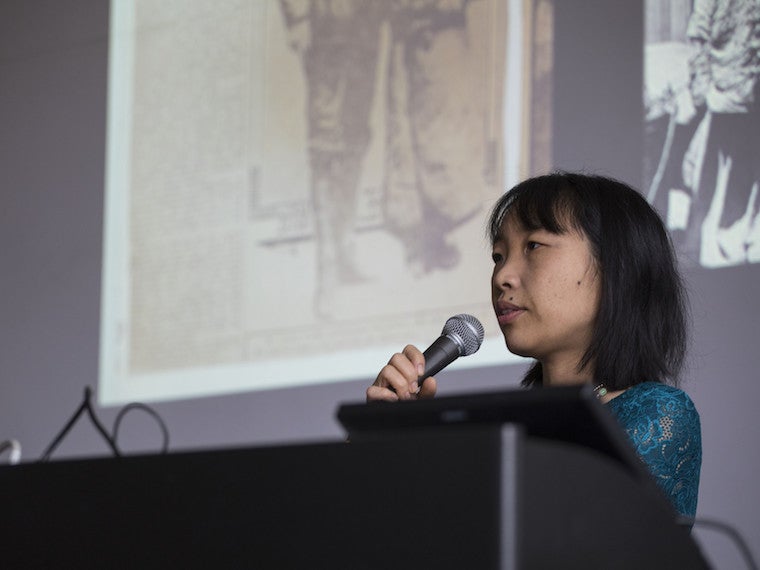 A professor speaks into a microphone at a podium.