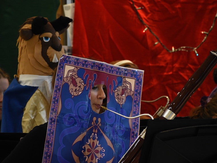 A girl wearing a card costume plays the bassoon.